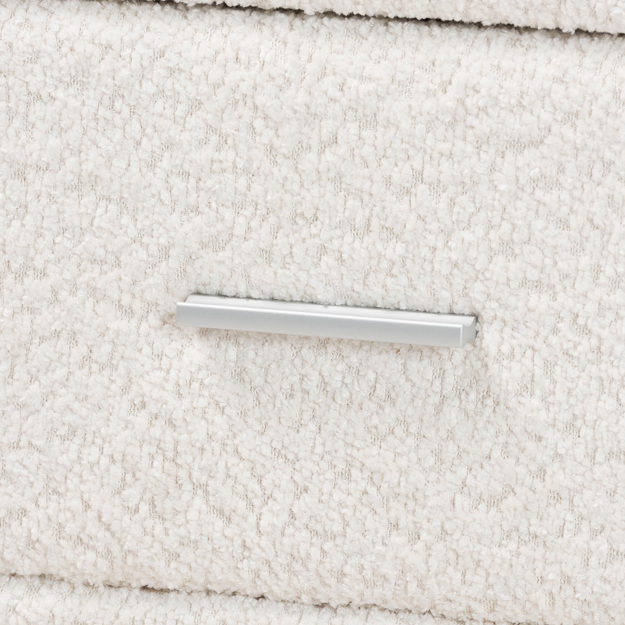 Close-up of a silver drawer handle on a white nightstand.