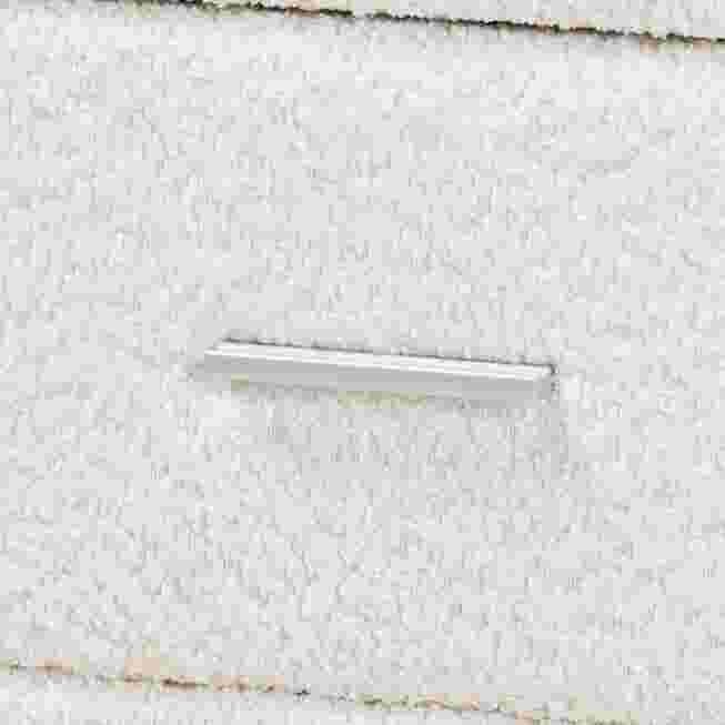 Close-up of a silver drawer handle on a white nightstand.