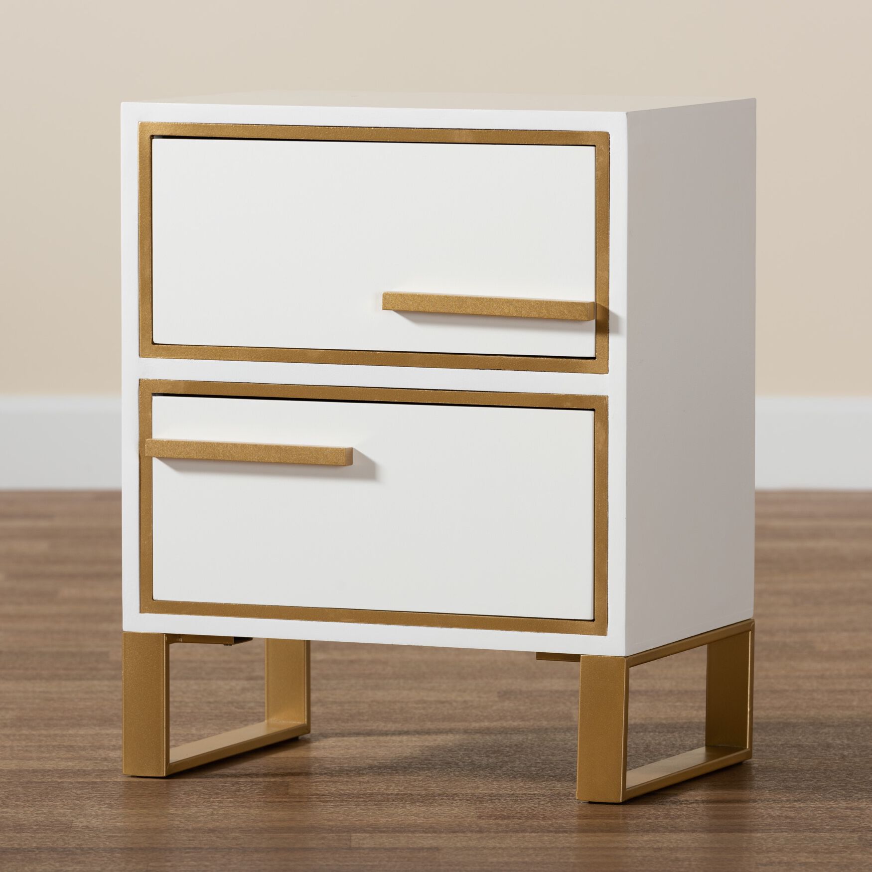 White nightstand with gold metal accents and two drawers on a wooden floor