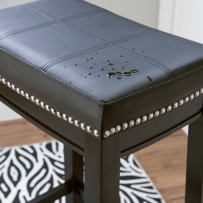 Close-up of Claridge bar stool nailhead trim on dark faux leather seat