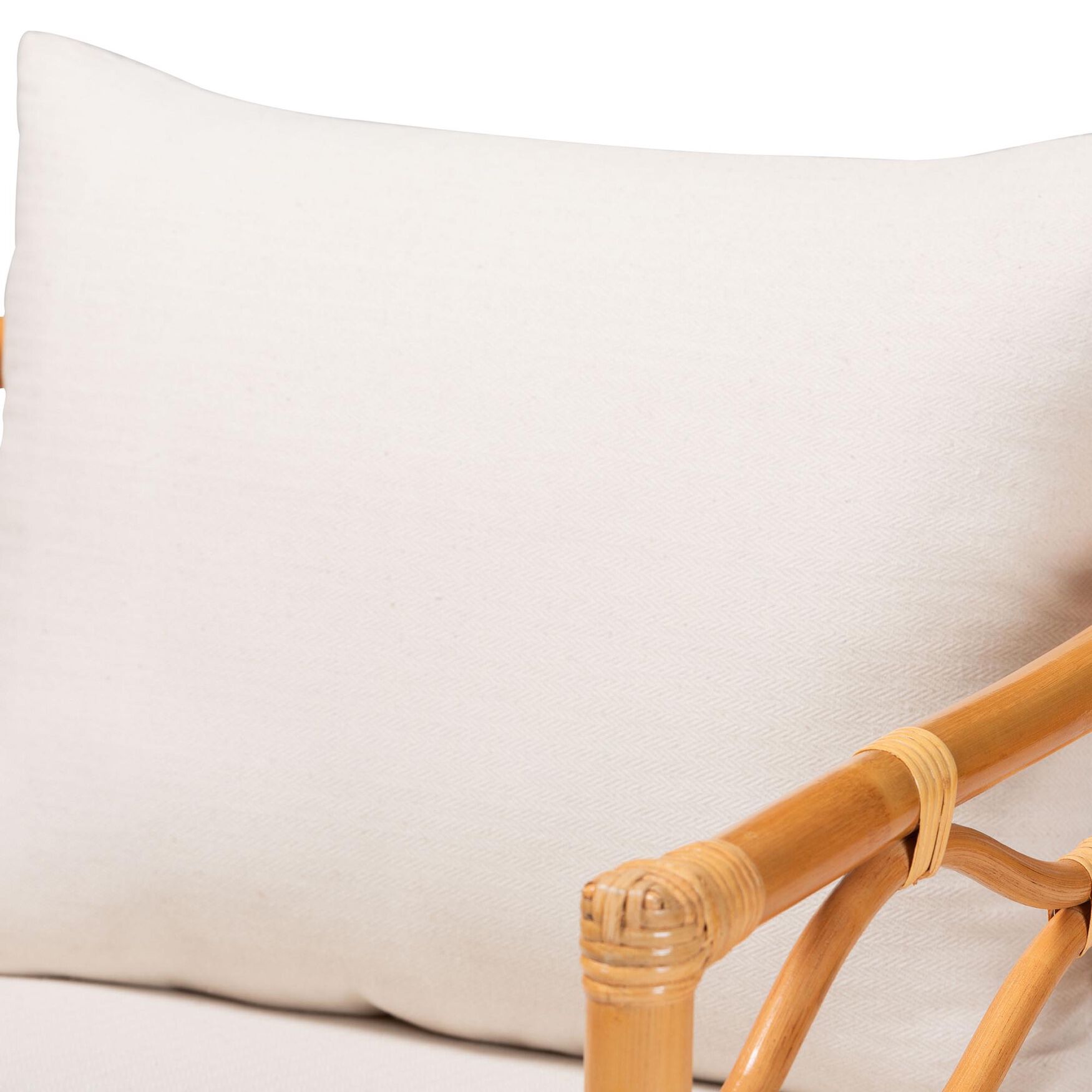 Close-up of white cushion on light honey rattan arm chair