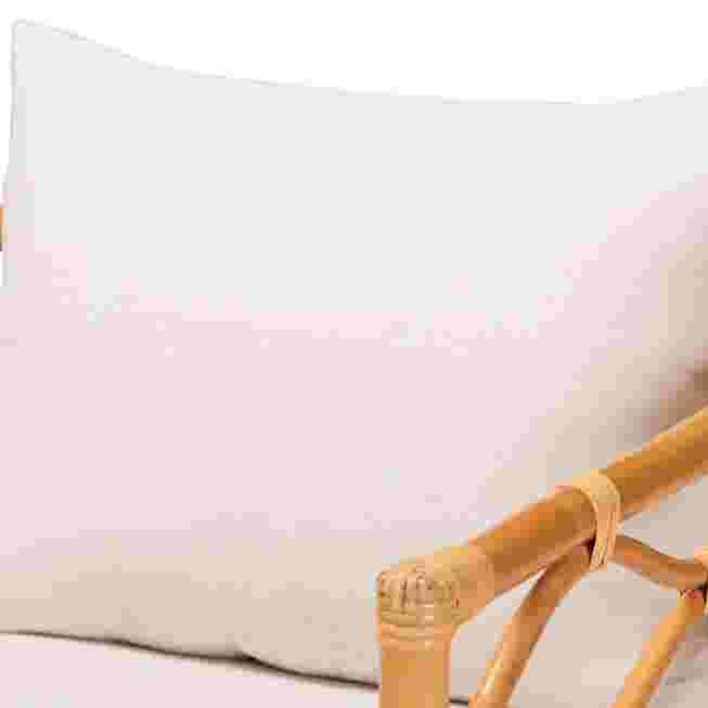 Close-up of white cushion on light honey rattan arm chair