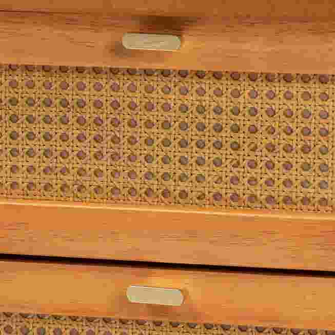 Close-up of drawer pull and rattan woven panel on golden brown nightstand