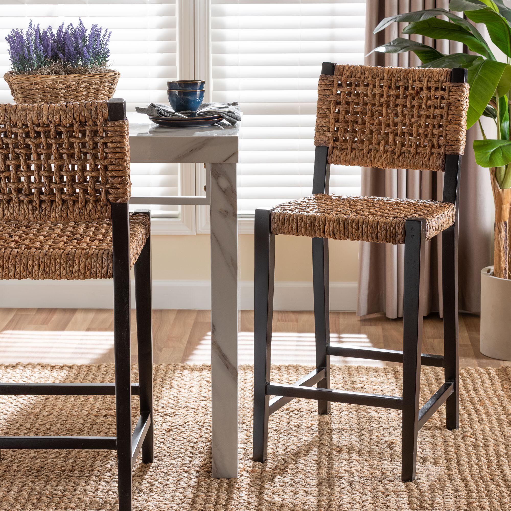 Two seagrass bar stools with black frames in a dining area.