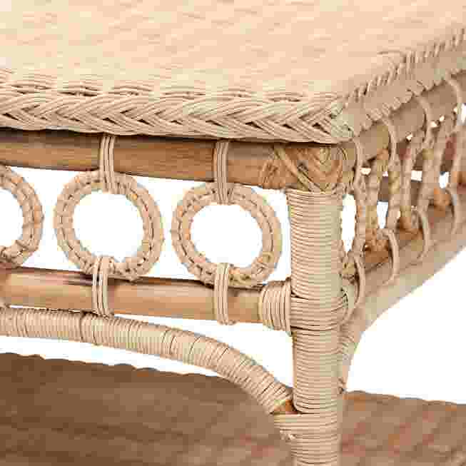 Close-up of the rattan coffee table's side, showing the woven pattern and circular cutouts.